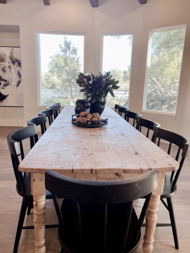 Dining area of great room. Vintage pine table with black spindle chairs, large black vases and magnolia branches. seats 12