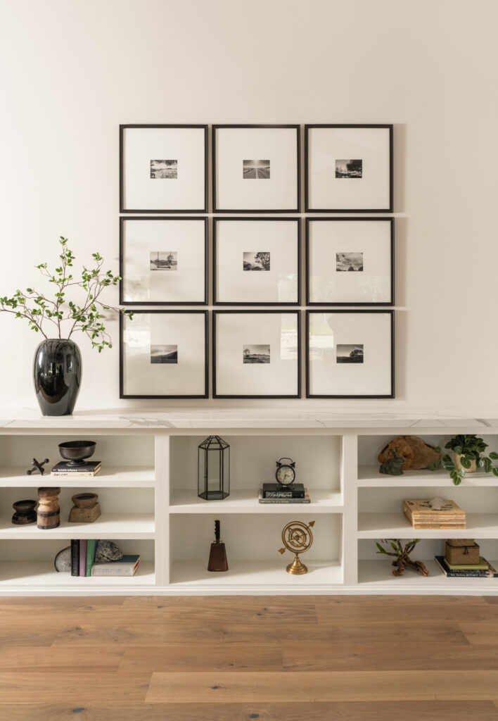 Modern Gallery wall with nine identical frames place in a three by three grid that is accompanied by a large black vase from CB2. baby grand piano and leather ottomans